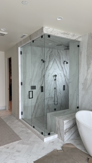 Massive Frameless Shower Door mounted with minimal black hardware.