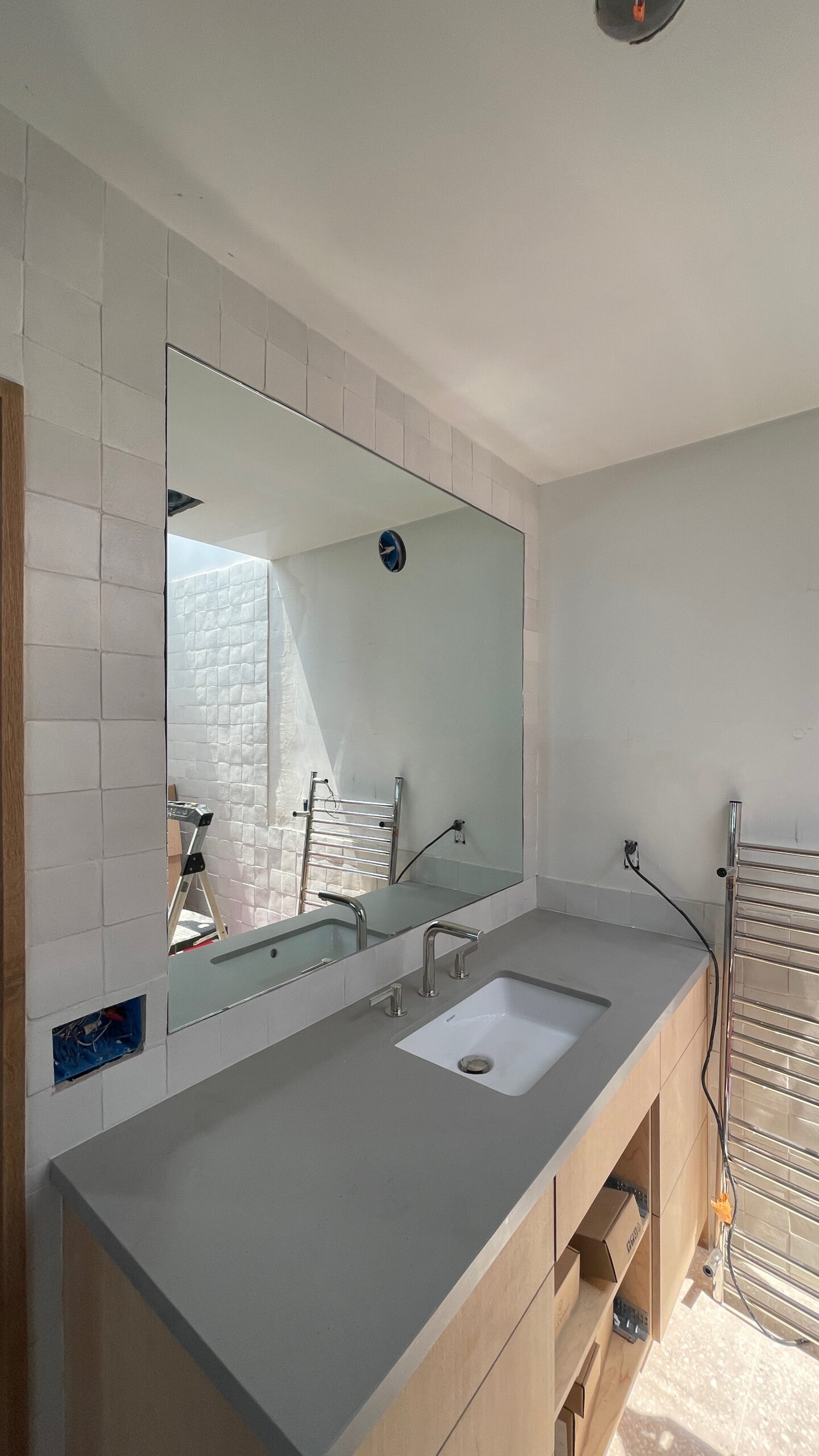 Large frameless vanity mirror installed above double sink with quartz countertop in modern bathroom