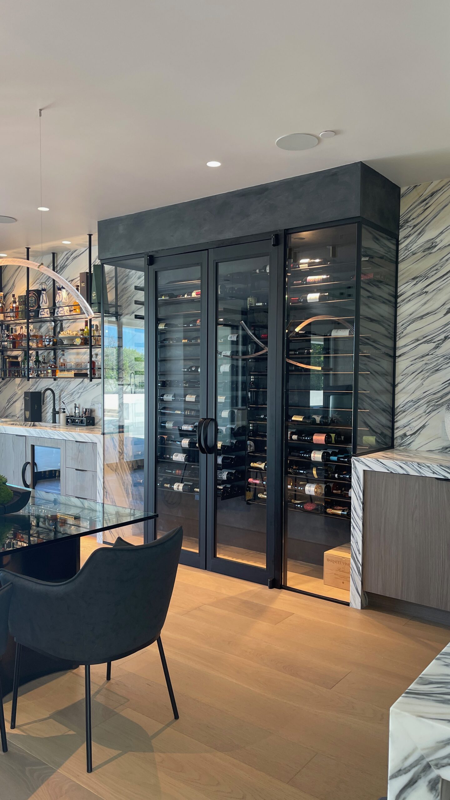 Custom glass wine room with black framed doors, sealed for temperature and humidity control in modern home