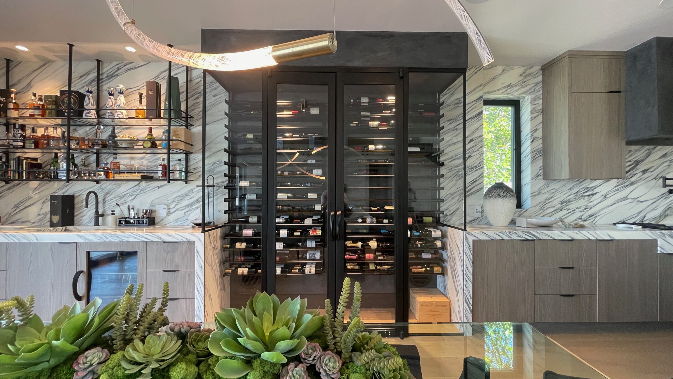 Custom glass wine room with black framed doors, sealed for temperature and humidity control in modern home